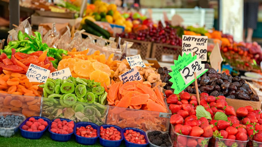 Fruits, including oranges, kiwis, strawberries, pineapples, and mangos for sale at the Rialto Market. Visiting the Rialto Market is one of the best activities to do in Venice in January.