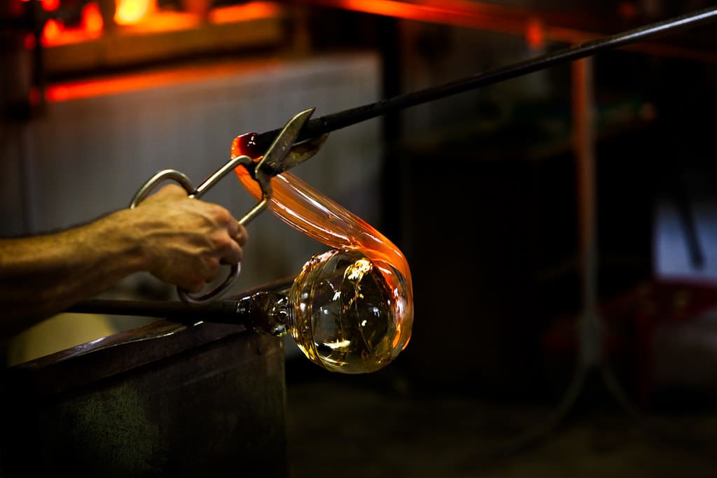 A hand with a scissors-like tool shaping some Murano glass. Attending a Murano glass workshop is one of the best activities to do in Venice in January.