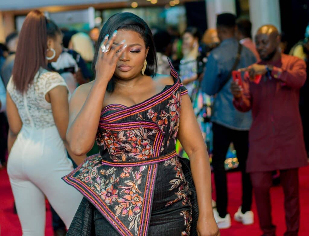 A photo of Funke Akindele, one of the most famous Nigerians, fixing her hair on the red carpet at an awards ceremony.