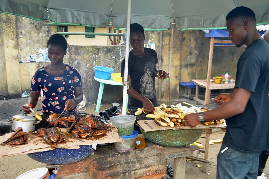 Three people by the roadside selling bole and fish.