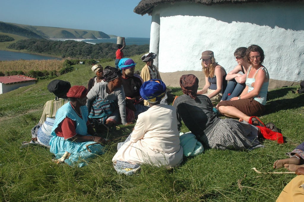 Picture of some tourists sitting and catching up with locals. Used to explain why travel can foster empathy: walking in another's shoes.