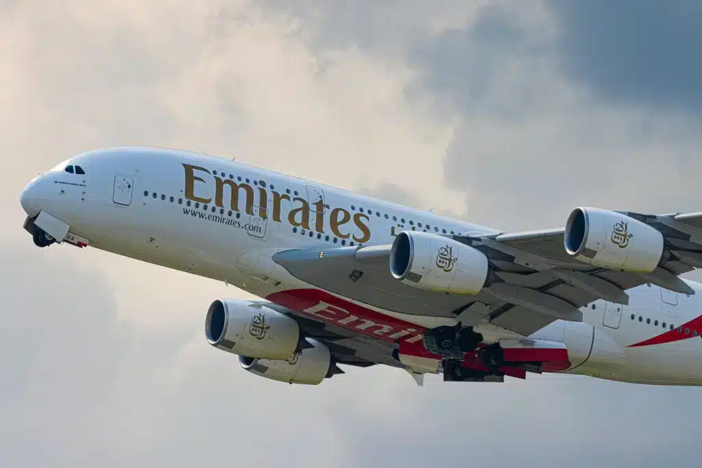 Emirates airplane soaring gracefully through the sky, showcasing the iconic logo and livery against a backdrop of clouds.